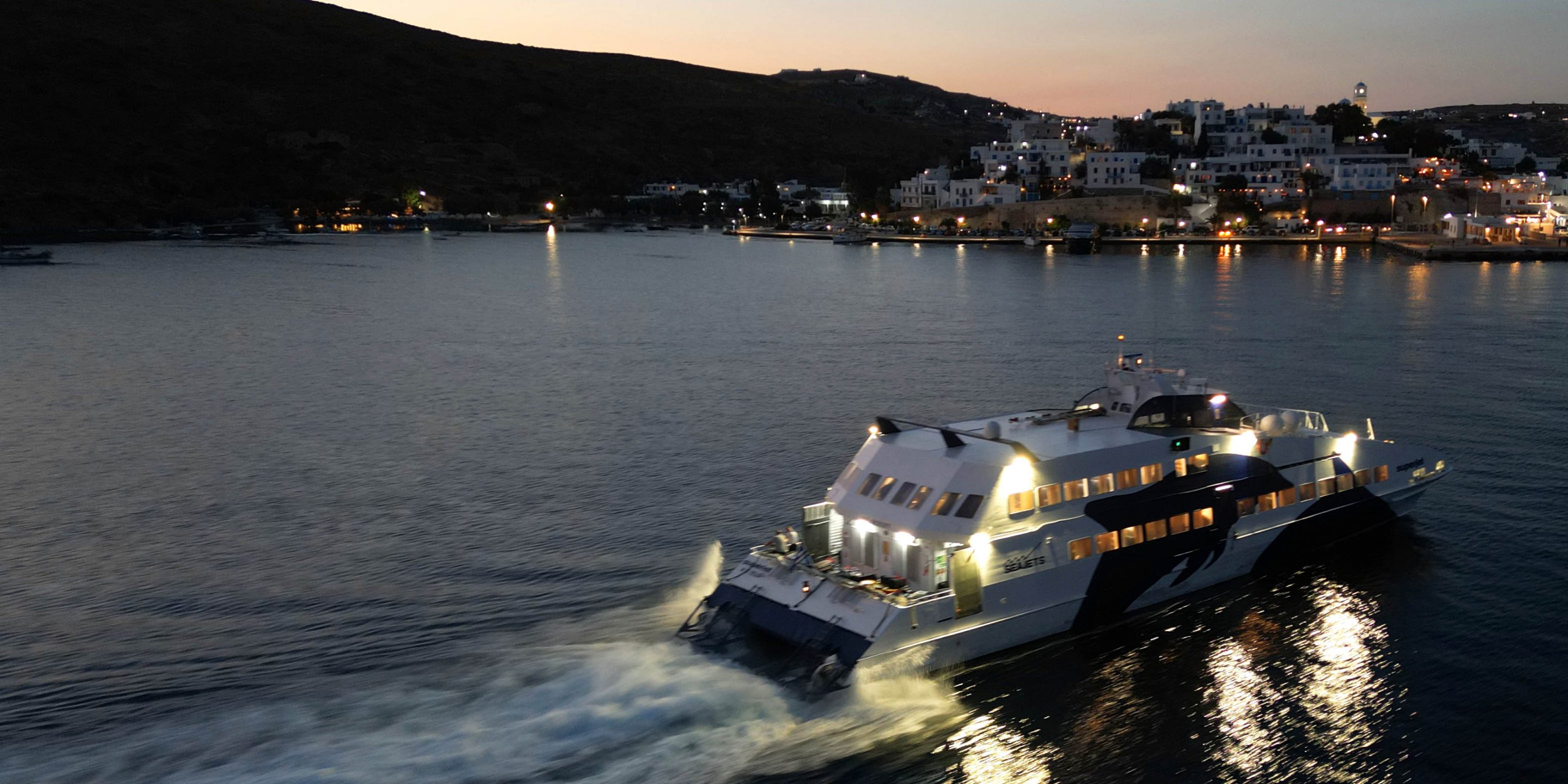 Il piccolo traghetto ad alta velocità SuperJet di Seajets in arrivo di notte nel porto di Adamas a Milos